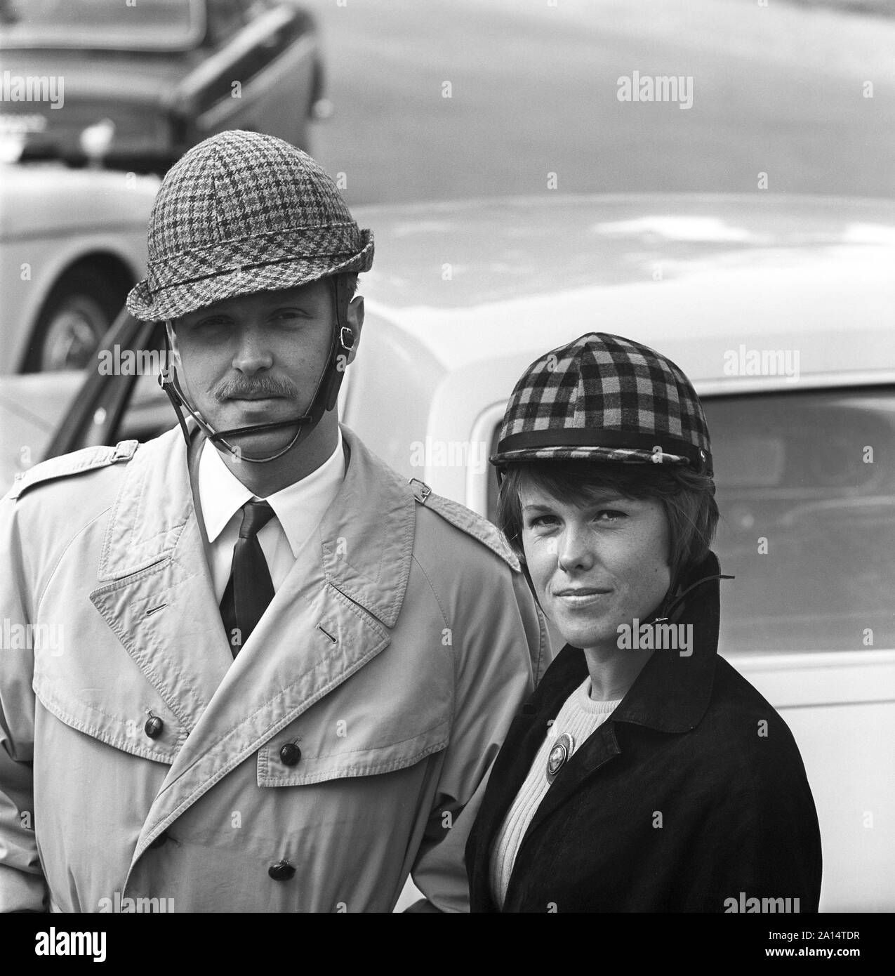 La guida negli anni sessanta. Caschi per auto è stato introdotto in Svezia a encrease sicurezza personale durante la guida di automobili. I costruttori di caschi spera che le vendite di loro sarebbe potenziata dal prossimo cambiamento dalla guida sul lato sinistro della strada sulla destra. Abbastanza stranamente meno incidenti poi è accaduto prima della modifica. Nella foto sono una giovane coppia che indossano i loro caschi che erano stati realizzati in maniera diversa per gli uomini e per le donne. La Svezia 1966 ref CV38-2 Foto Stock