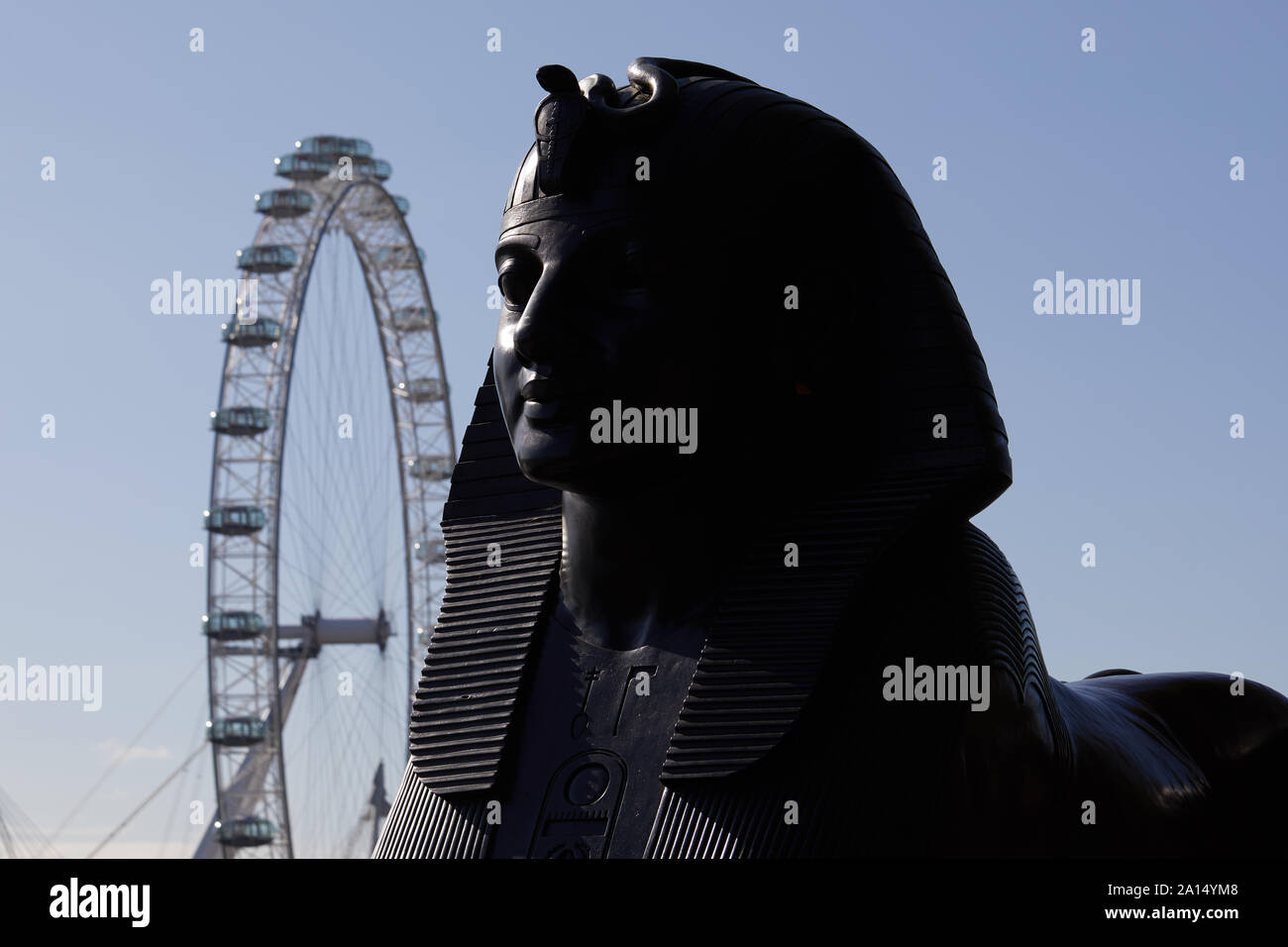 London, Regno Unito - 17 Settembre 2019: la testa di uno di bronzo egizio-style sfinge che fiancheggiano il Cleopatra Needle davanti al London Eye. Foto Stock