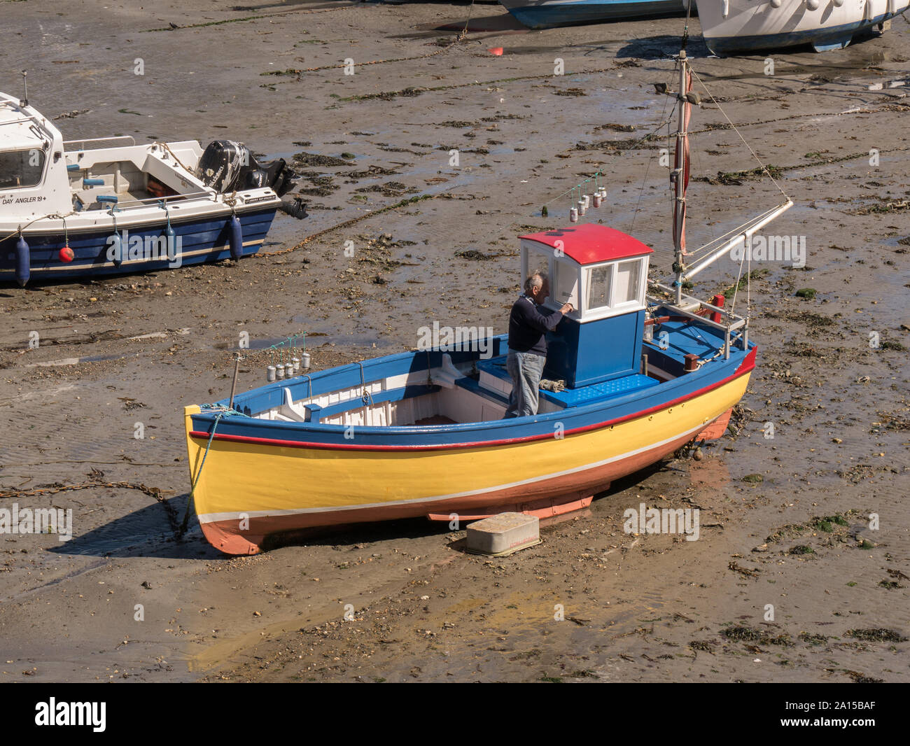 Un uomo pittura una barca a Porthleven in Cornovaglia Foto Stock