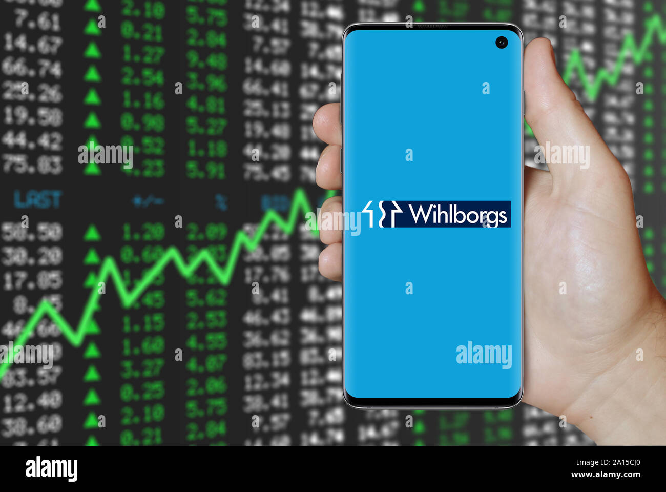 Un uomo possiede uno smartphone visualizzando il logo della società Wihlborgs elencati su OMX di Stoccolma. Stock positivo dei dati di mercato. Credito: PIXDUCE Foto Stock