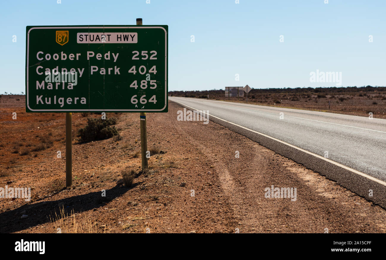 Un australiano cartello stradale con le distanze e i nomi di città tra Coober Pedy e Kulgera lungo la Stuart Highway tra SA e NT. Foto Stock