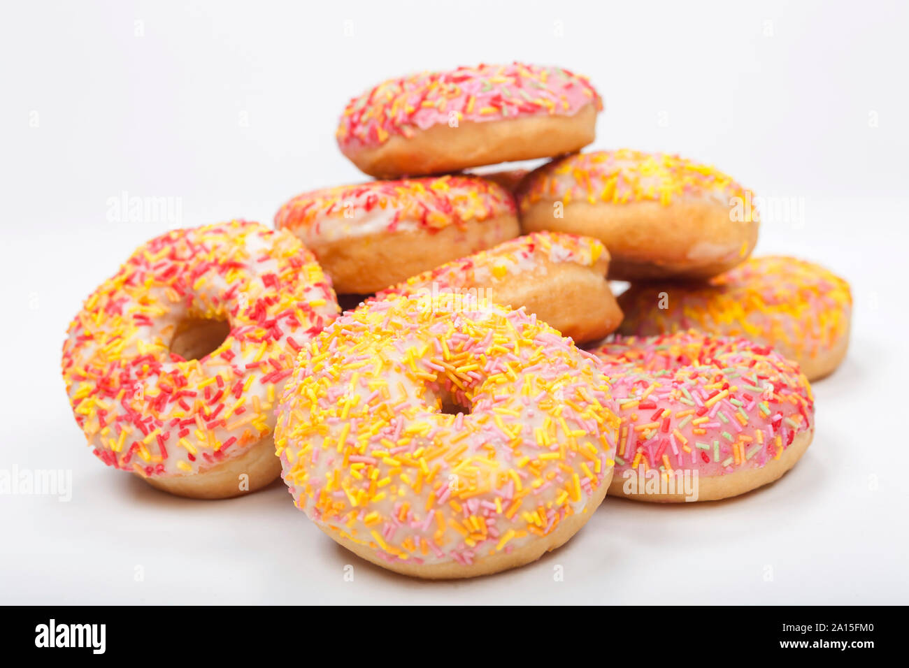 Donuts o ciambelle con glassa colorata o glassa e spruzza fotografato su sfondo bianco Foto Stock