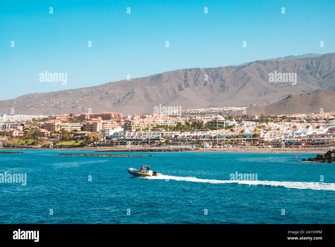 Imbarcazione a motore in costa dell'oceano con spiaggia e hotel in background, Tenerife Foto Stock