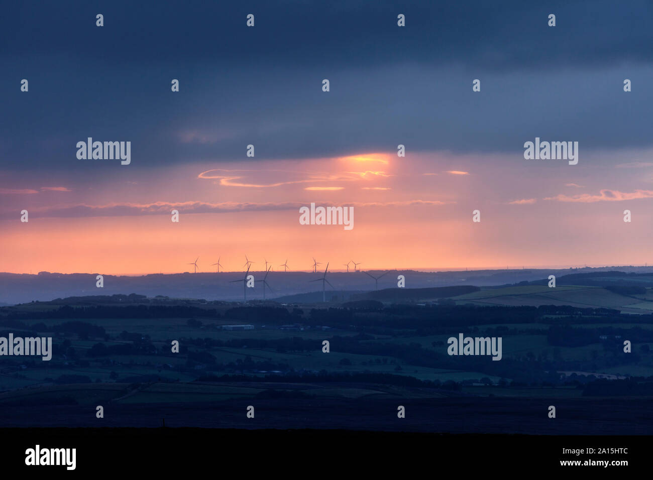 Distanti le turbine a vento sotto un cielo drammatico di Sunrise, visto dal North Pennines nella Contea di Durham, Regno Unito Foto Stock