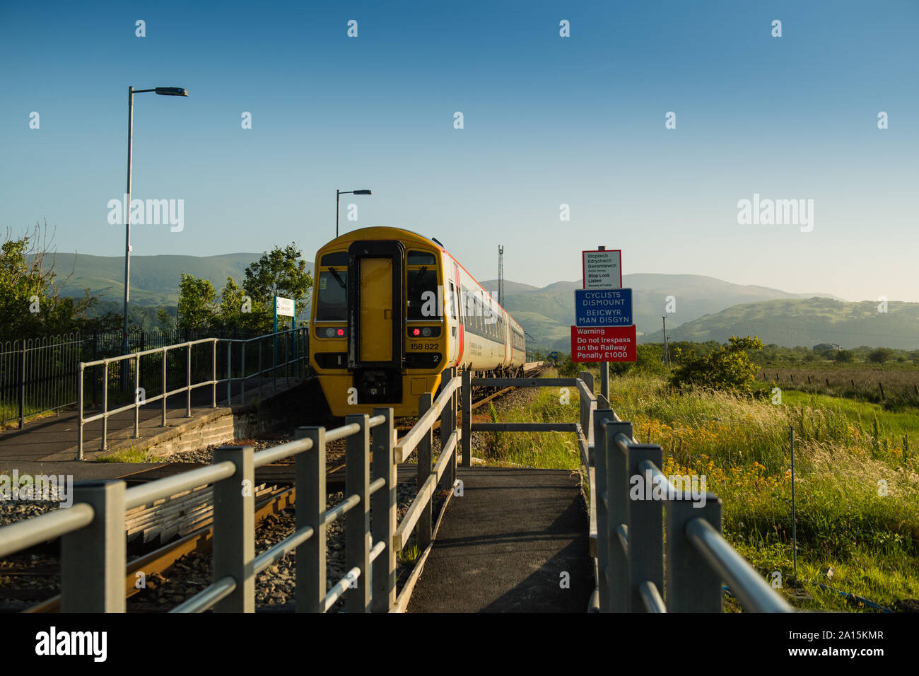 I mezzi di trasporto pubblico nel Regno Unito: di un sistema di trasporto per il Galles DMU [diesel multiple unit] treno locale avvicinando Dyfi stazione di giunzione di arresto su una soleggiata mattina d'Estate, Wales UK Foto Stock