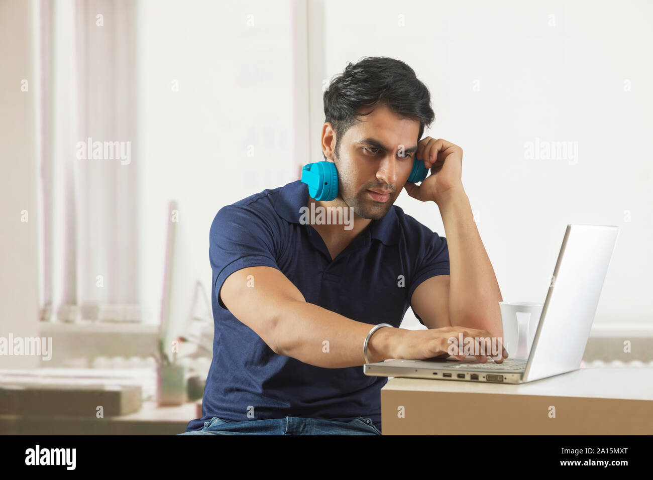 Giovane ragazzo che lavorano in ufficio utilizzando la cuffia e il computer portatile Foto Stock