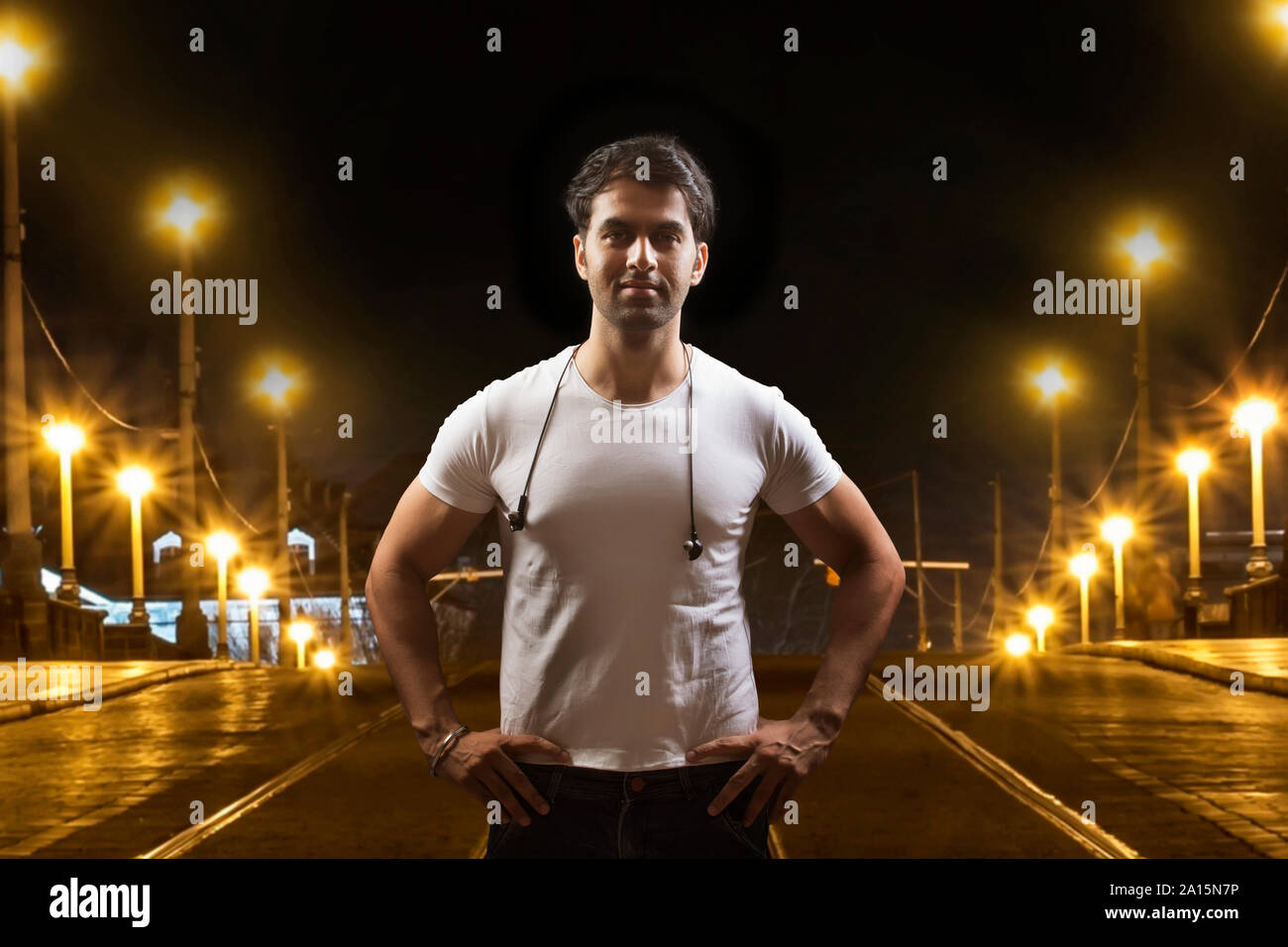 Giovane uomo in piedi con le mani sui fianchi sulla via della città di notte Foto Stock
