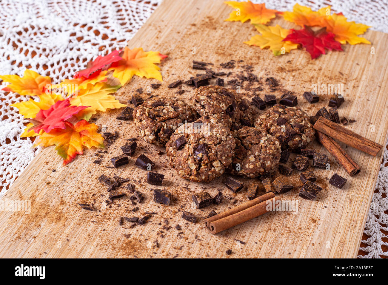 Biscotti al cioccolato su un tavolo di legno con bastoncini di cannella. In autunno il cibo stile foto con foglie Foto Stock