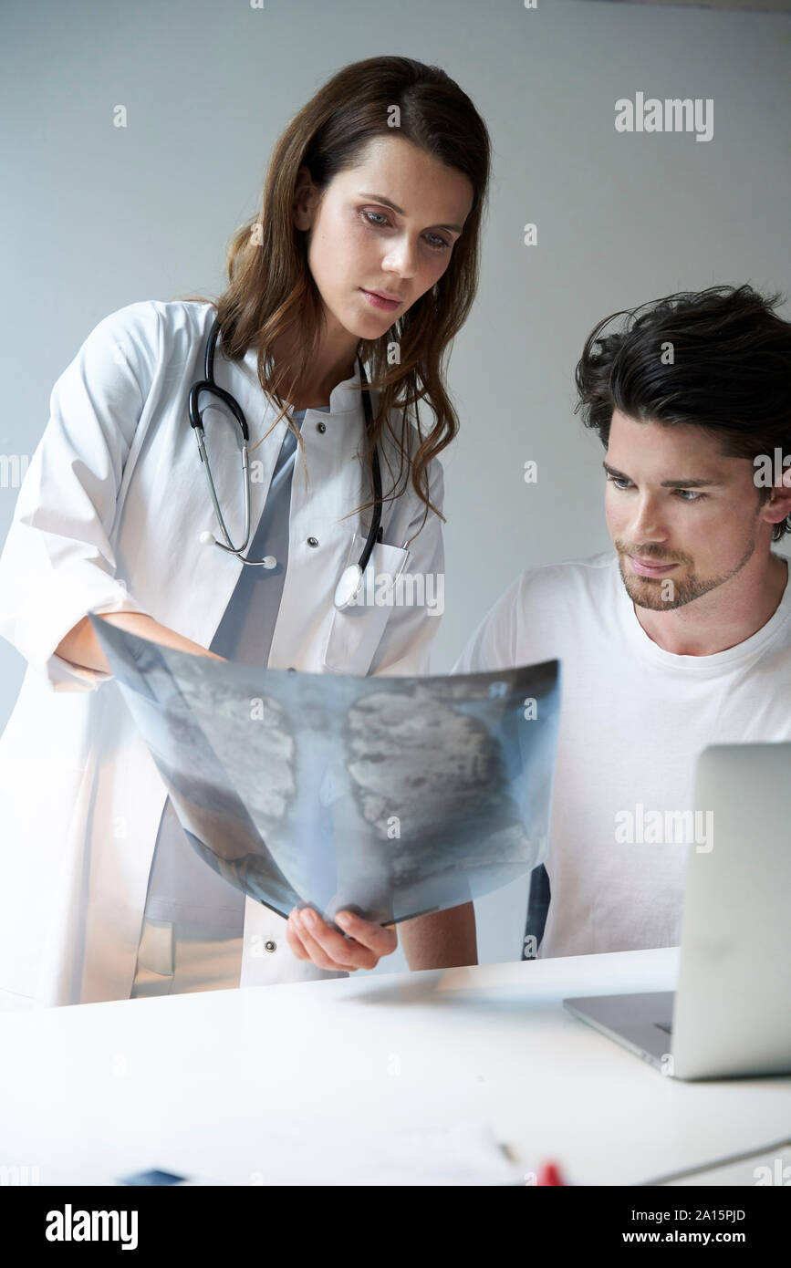 Due medici con l'immagine a raggi x alla scrivania Foto Stock