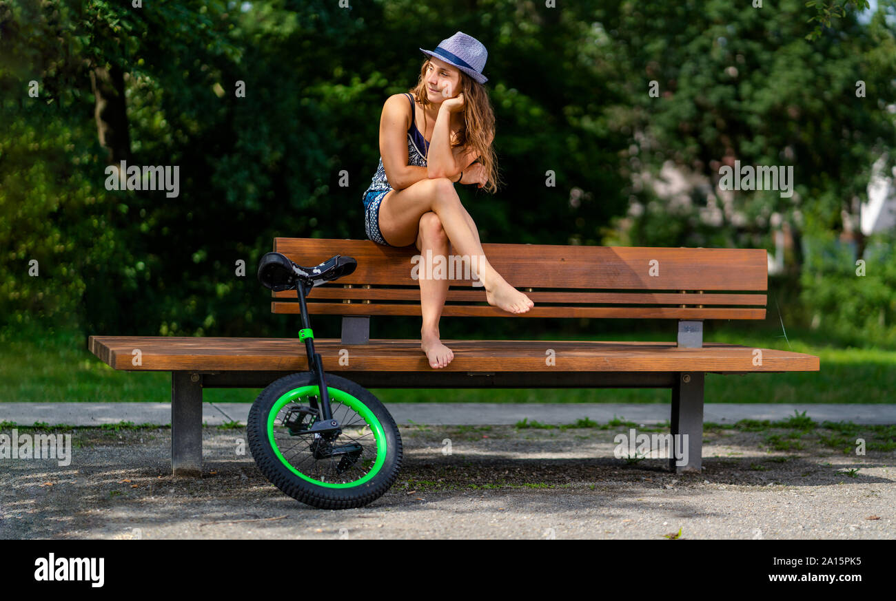 Giovane donna con monociclo seduta su una panchina nel parco Foto Stock