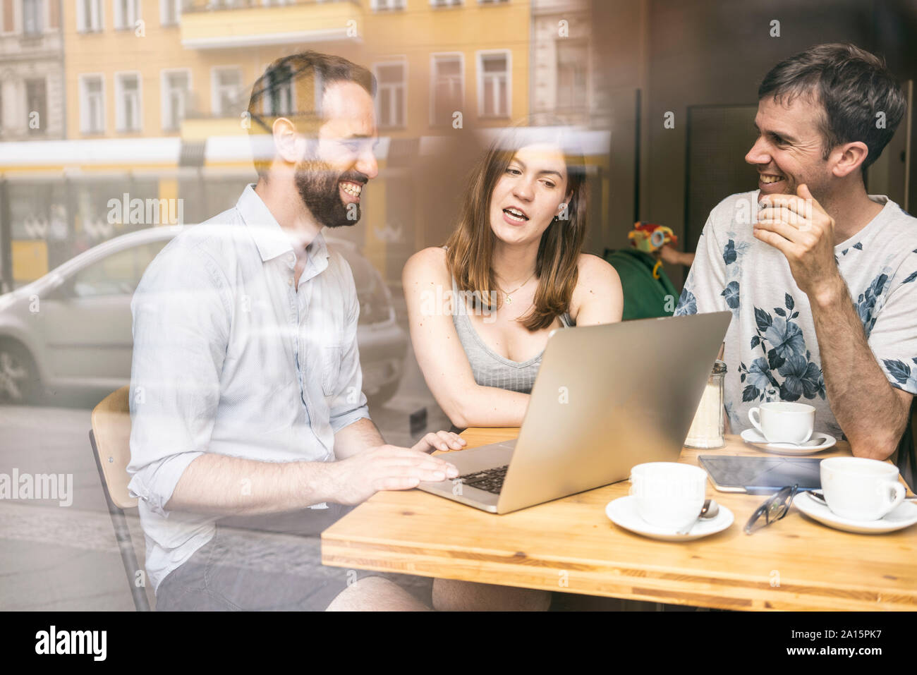 Gruppo di amici seduti insieme in un cafe con il computer portatile Foto Stock