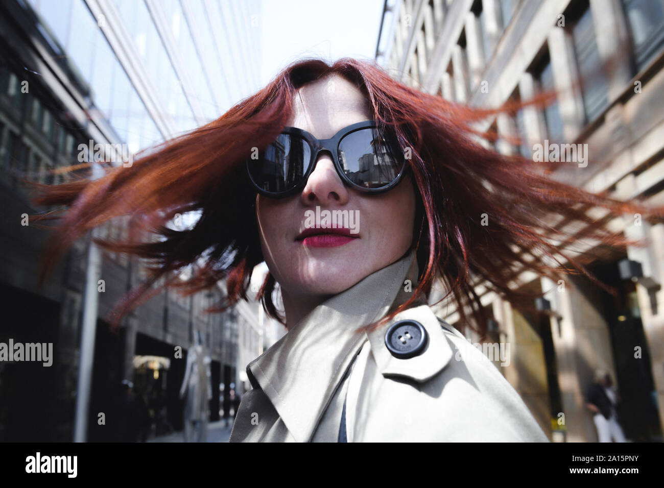 Ritratto di una donna elegante con occhiali da sole e trench Foto Stock