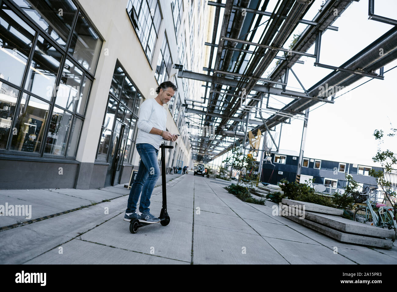 Uomo maturo con lo smartphone e scooter elettrico Foto Stock