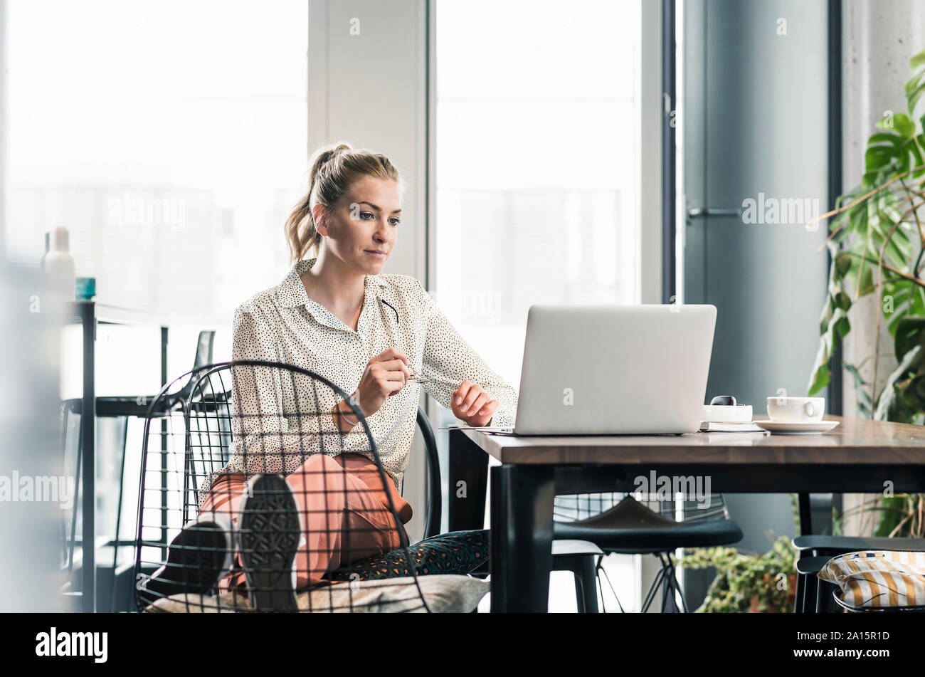 Imprenditrice seduta a tavola in ufficio utilizzando laptop Foto Stock