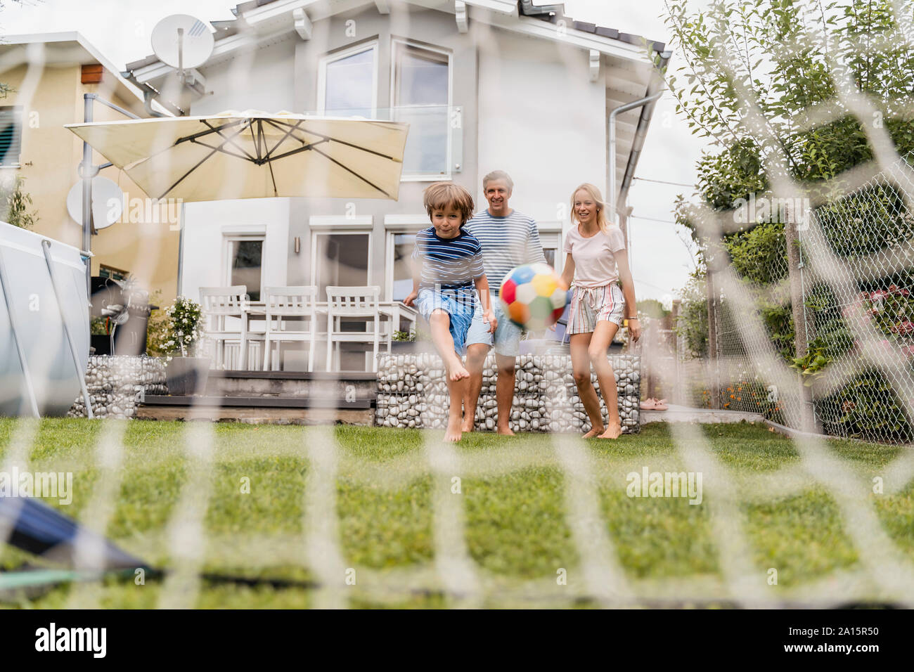 La famiglia felice a giocare a calcio in giardino Foto Stock