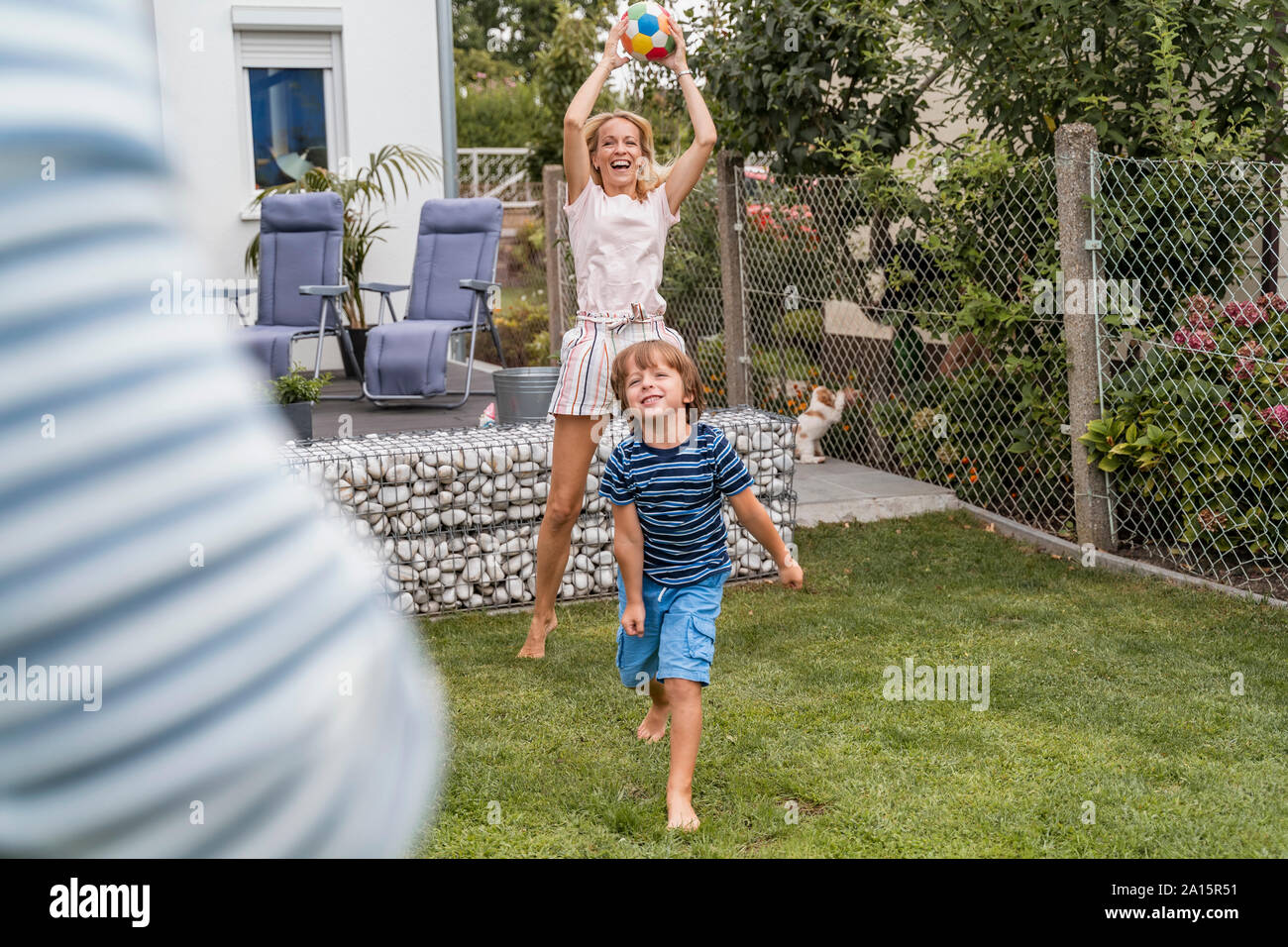 La famiglia felice a giocare a calcio in giardino Foto Stock