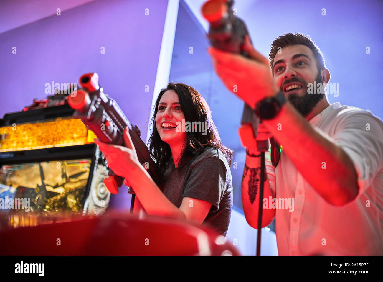 Coppia felice giocando e riprese con i fucili in una sala giochi Foto Stock