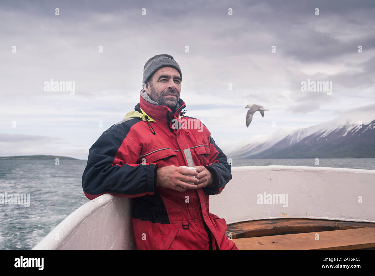 Uomo maturo guardando il mare, gite in barca sul fiordo Eyjafjordur, Islanda Foto Stock