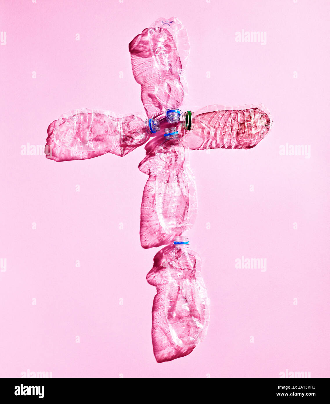 Le bottiglie di plastica, forma a croce su sfondo rosa Foto Stock