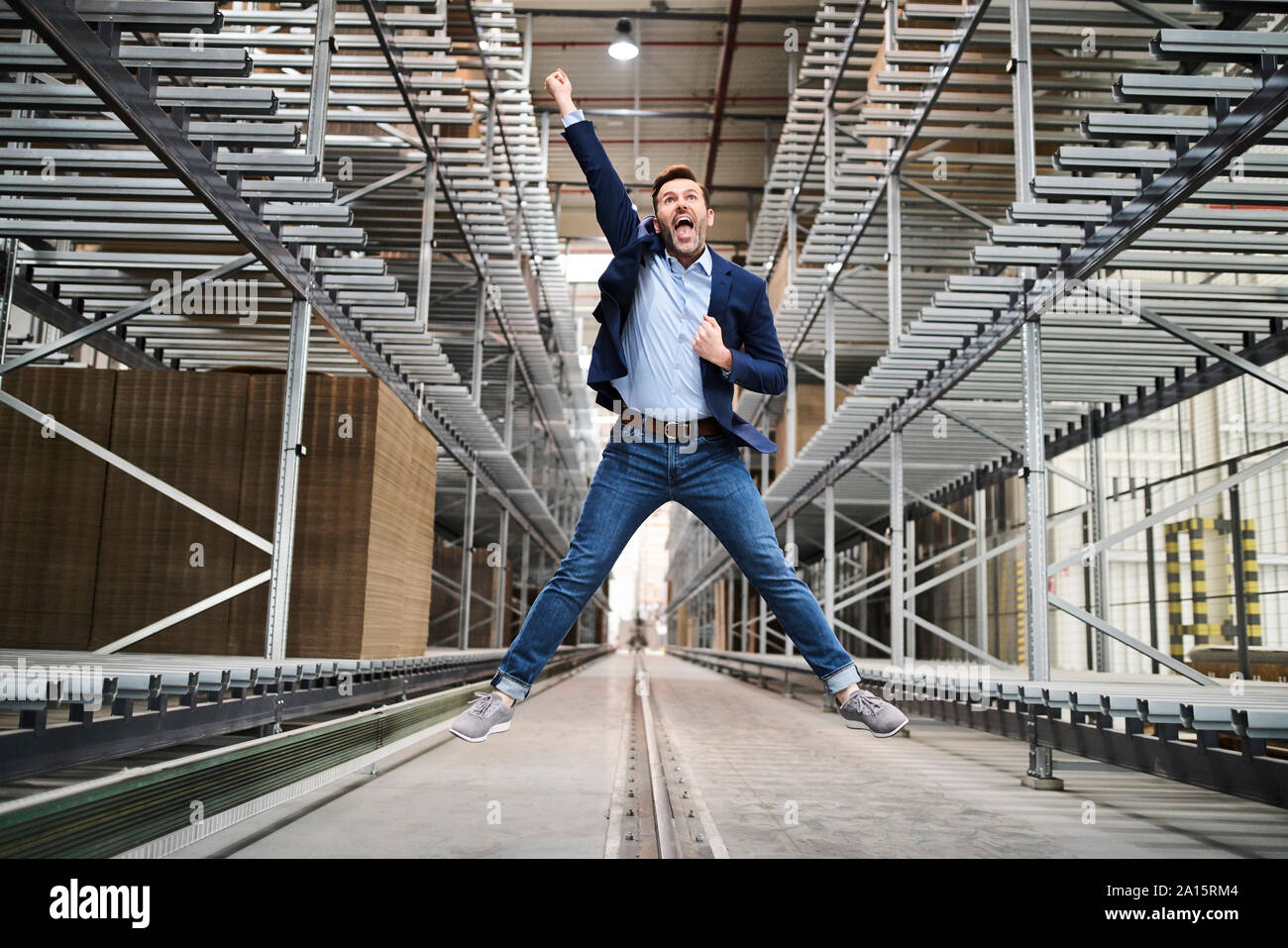 Imprenditore entusiasta jumping in fabbrica Foto Stock