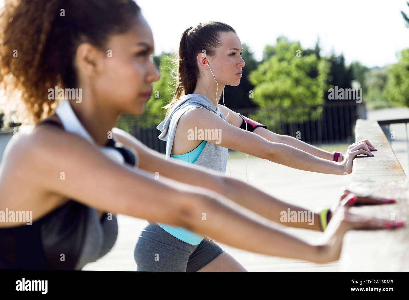 Sportivo di due giovani donne stiramento sulla ringhiera del ponte Foto Stock