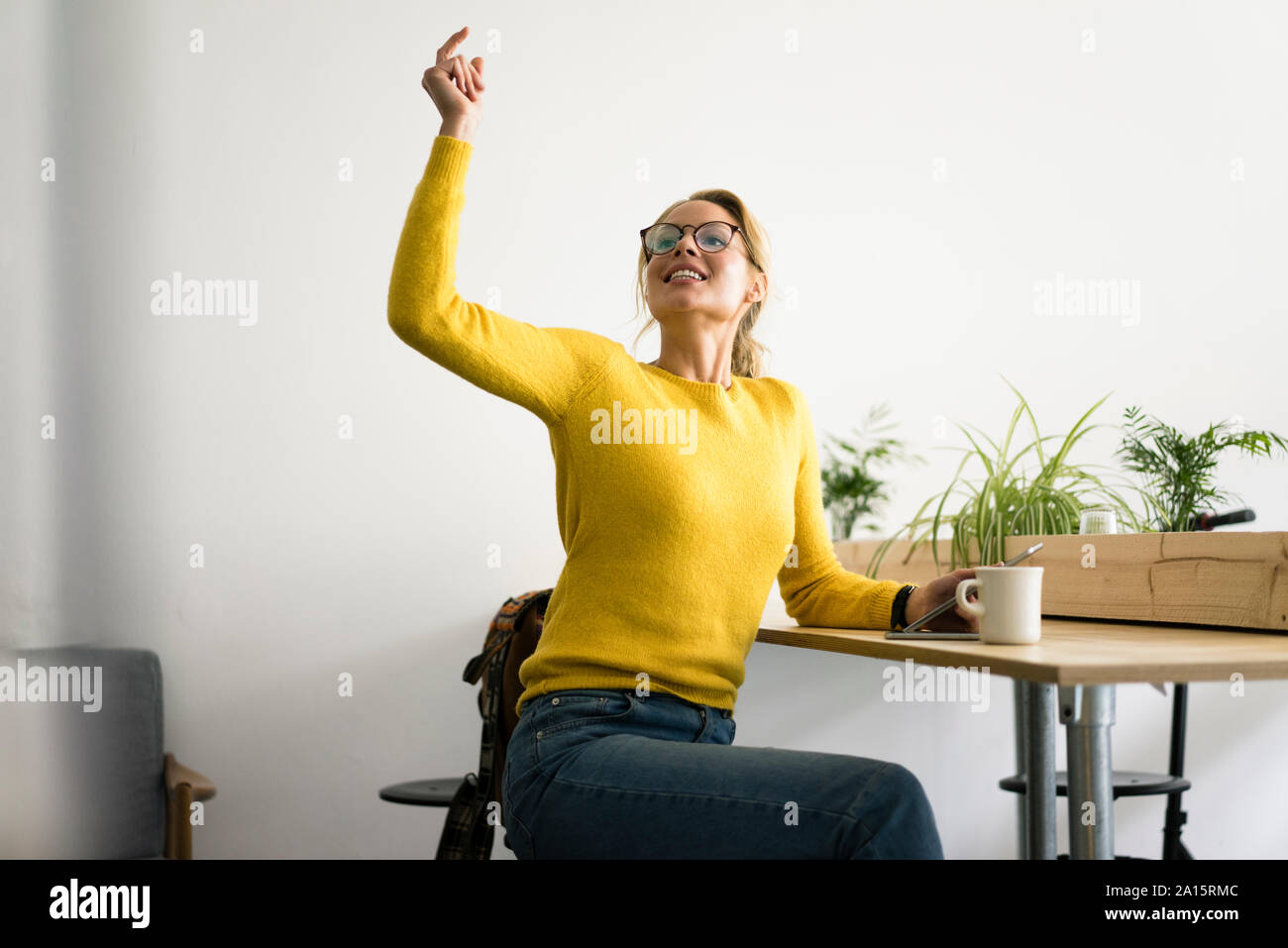 Giovane donna seduta in un coffee shop, facendo clic su dita per ordinare qualcosa Foto Stock