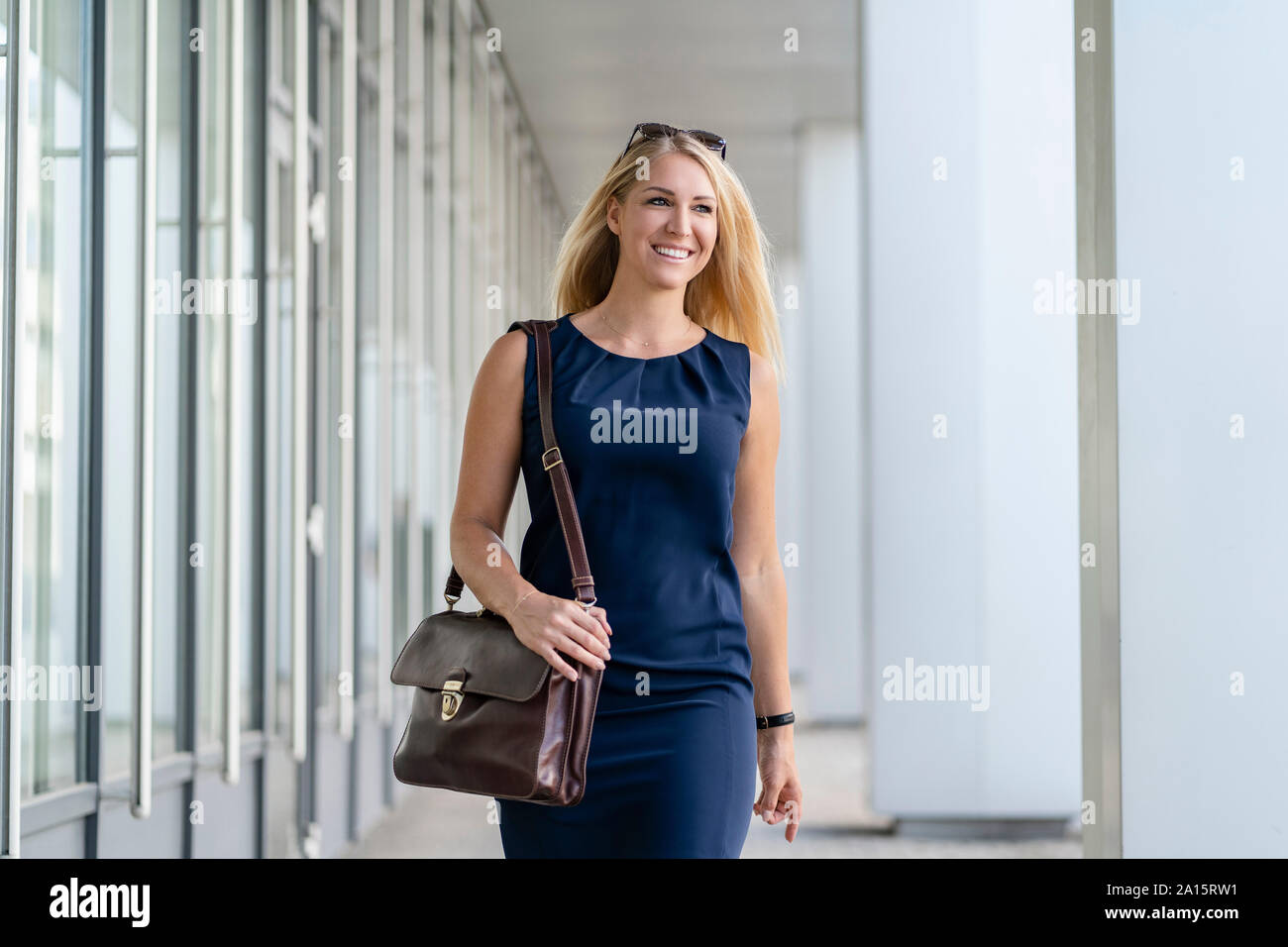 Ritratto di sorridente bionda imprenditrice con valigetta blu da indossare abiti estivi Foto Stock