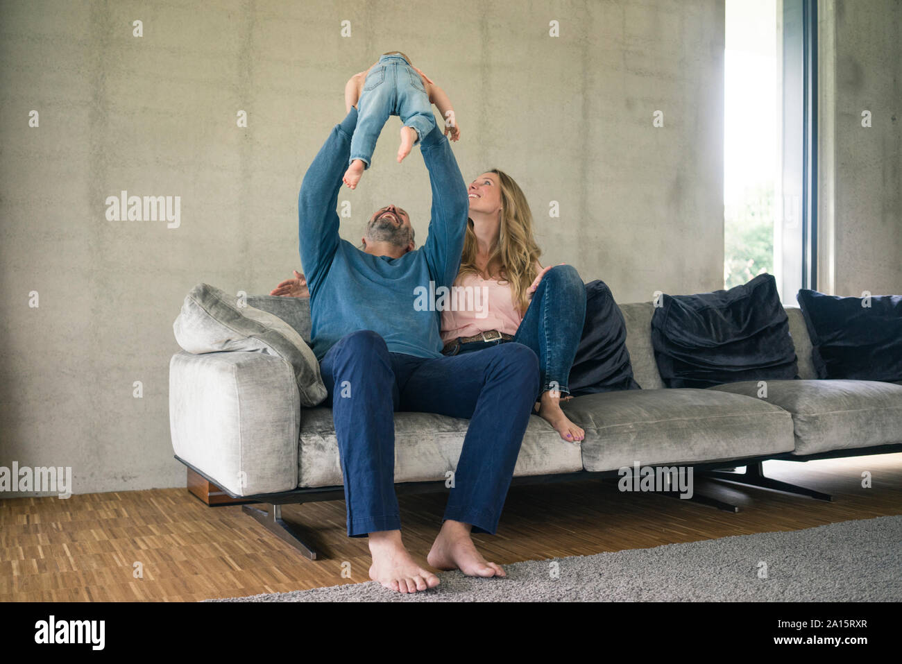 La famiglia felice di tre giocando sul lettino a casa Foto Stock