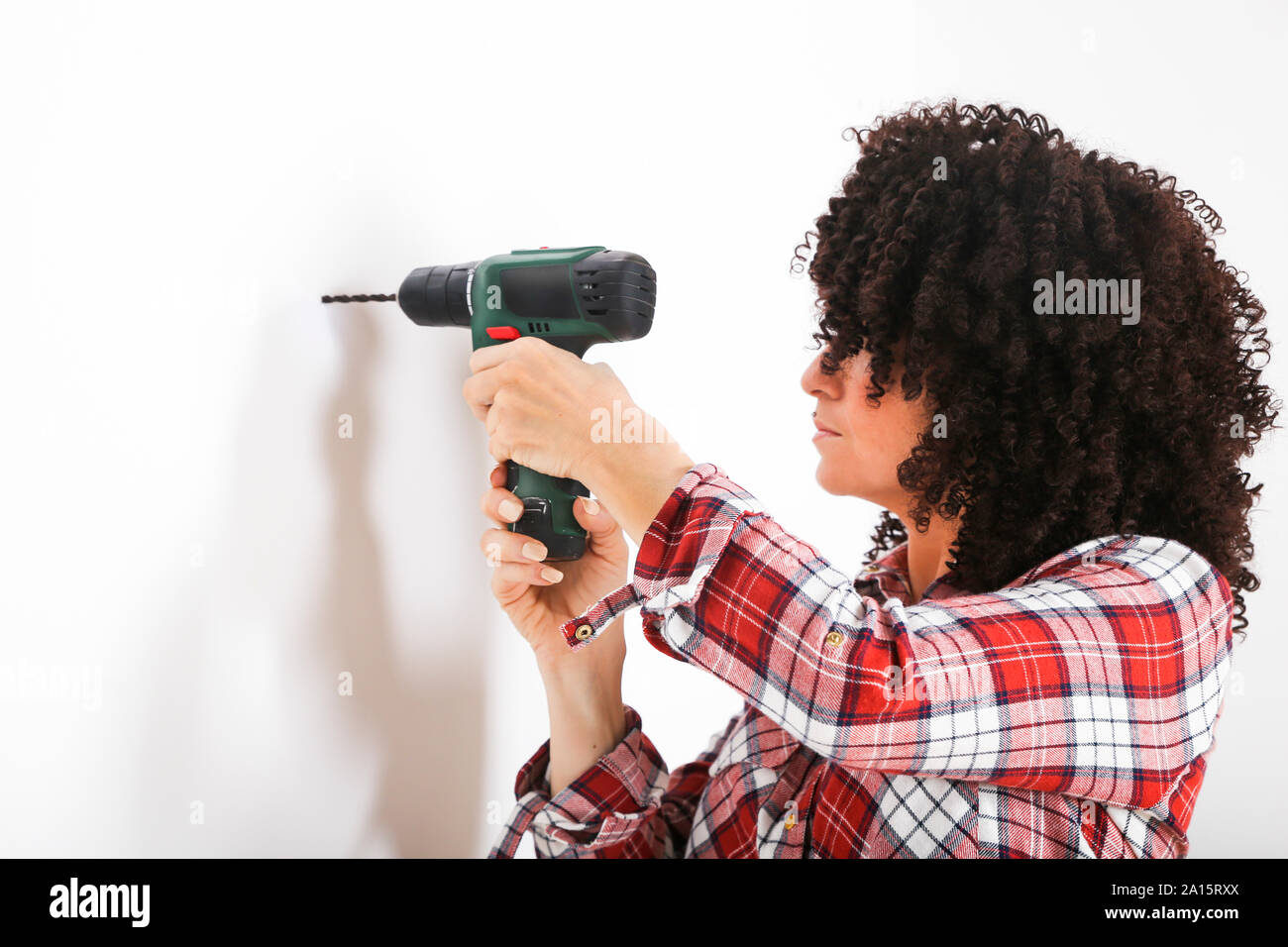 Donna che utilizza un trapano portatile, la marcatura con matita su una parete Foto Stock