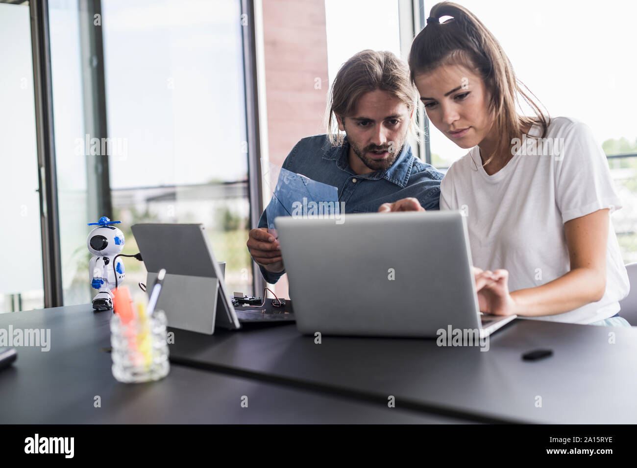 Giovane uomo e donna che lavorano insieme su laptop alla scrivania in ufficio Foto Stock