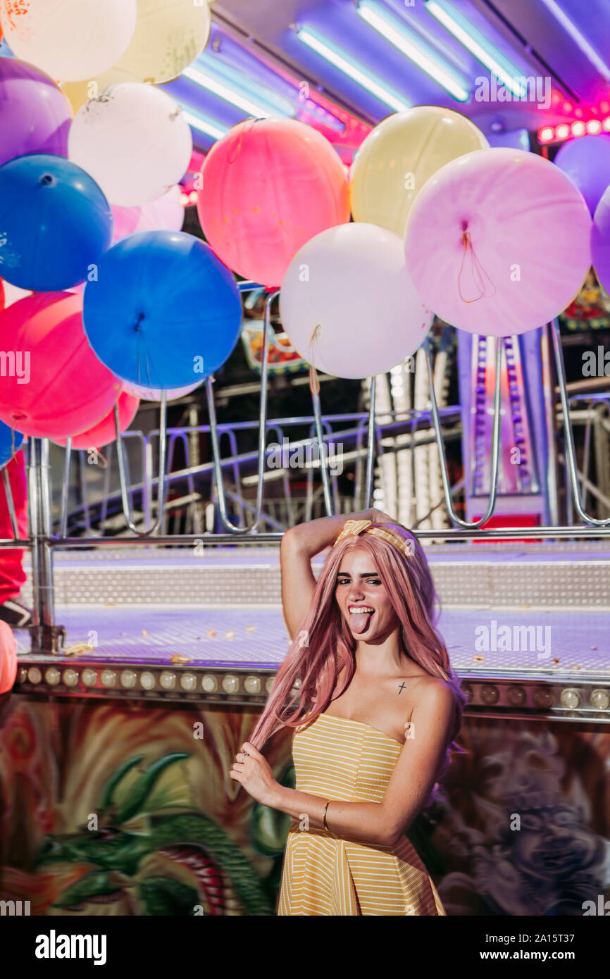 Felice giovane donna su un luna park di notte spuntavano lingua Foto Stock