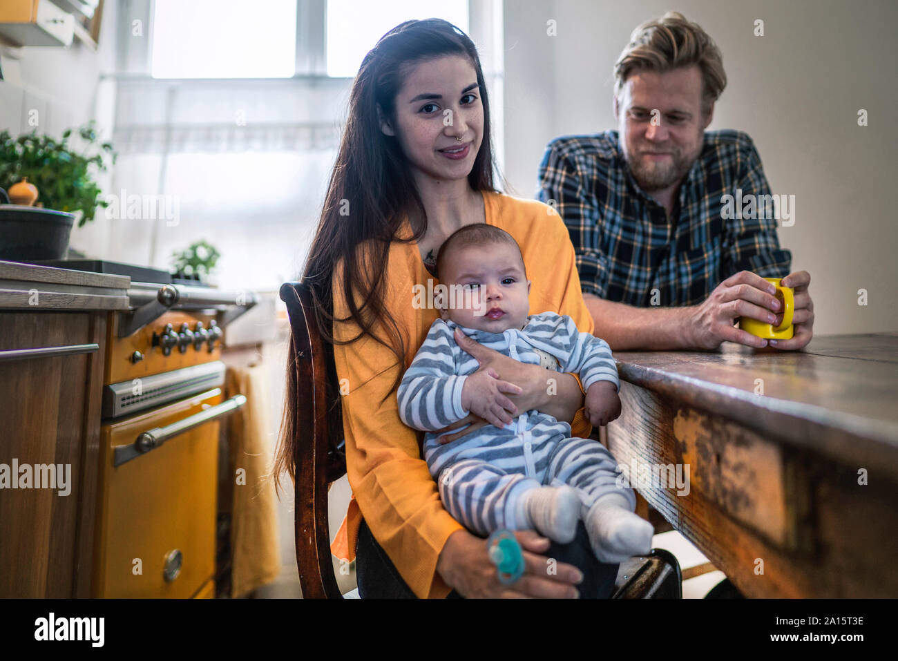 Ritratto di famiglia con bambino seduto al tavolo della cucina a casa Foto Stock