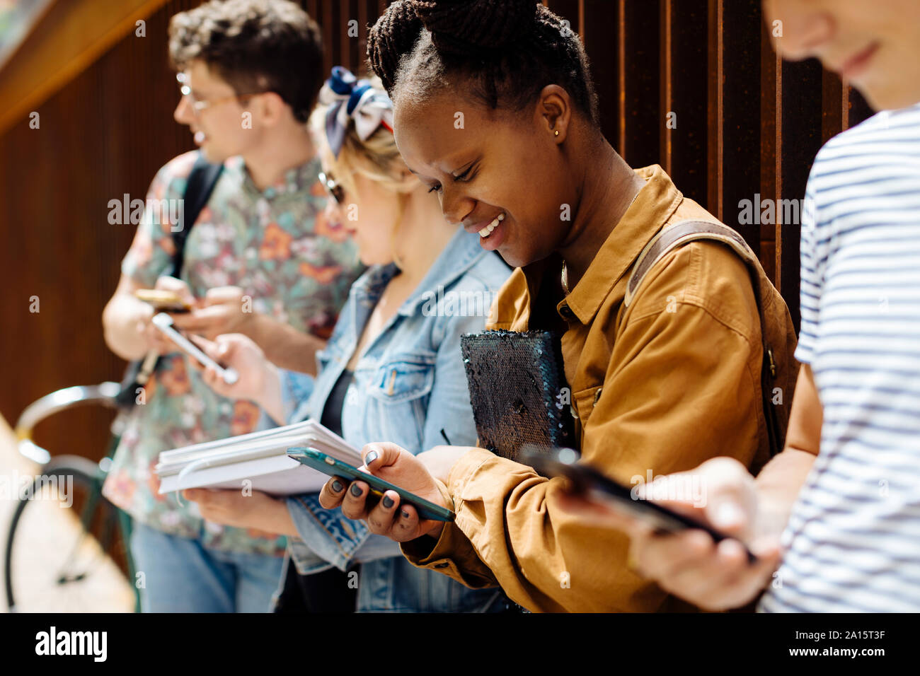 Gli studenti riuniti in un cortile, parlando, smartphone unsing Foto Stock
