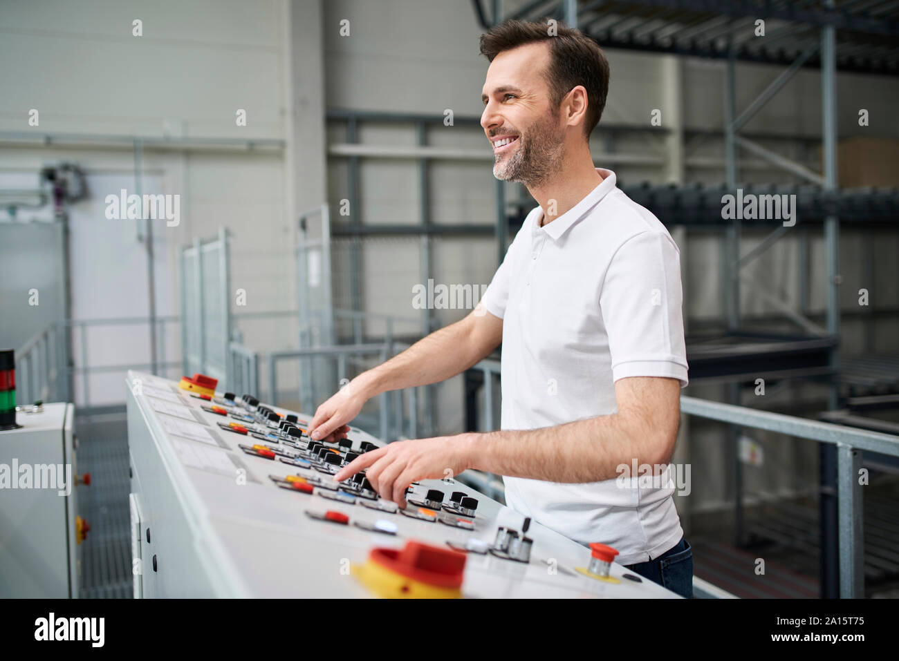 Uomo sorridente di funzionamento del pannello di controllo in una fabbrica Foto Stock