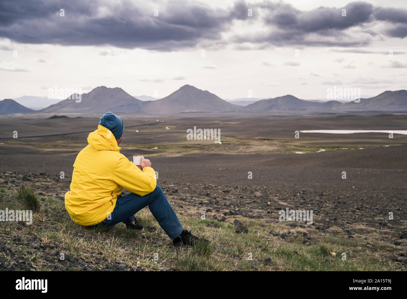 Uomo di bere caffè, guardando il paesaggio in Islanda Foto Stock