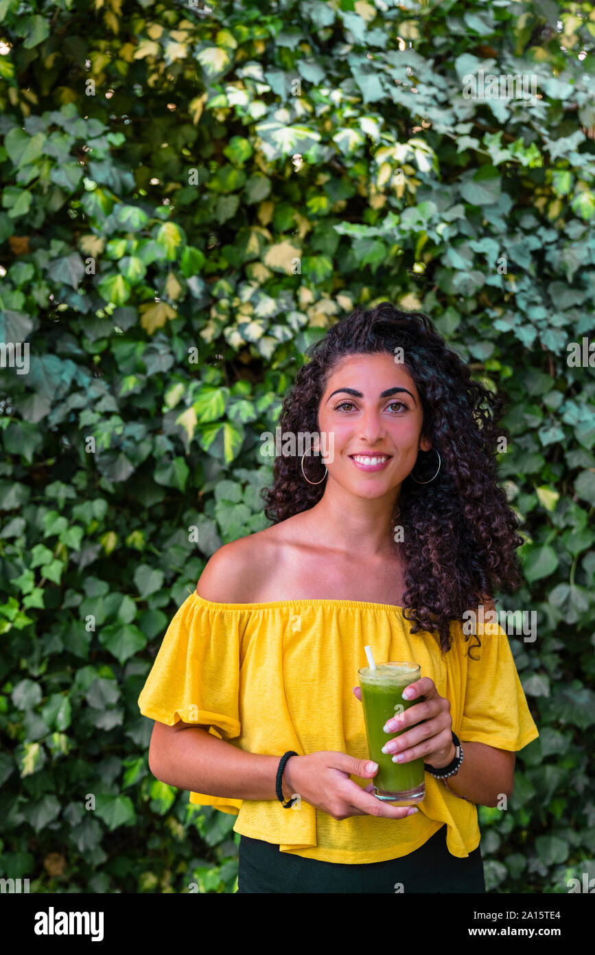 Ritratto di sorridente giovane donna in possesso di una bibita salutare Foto Stock