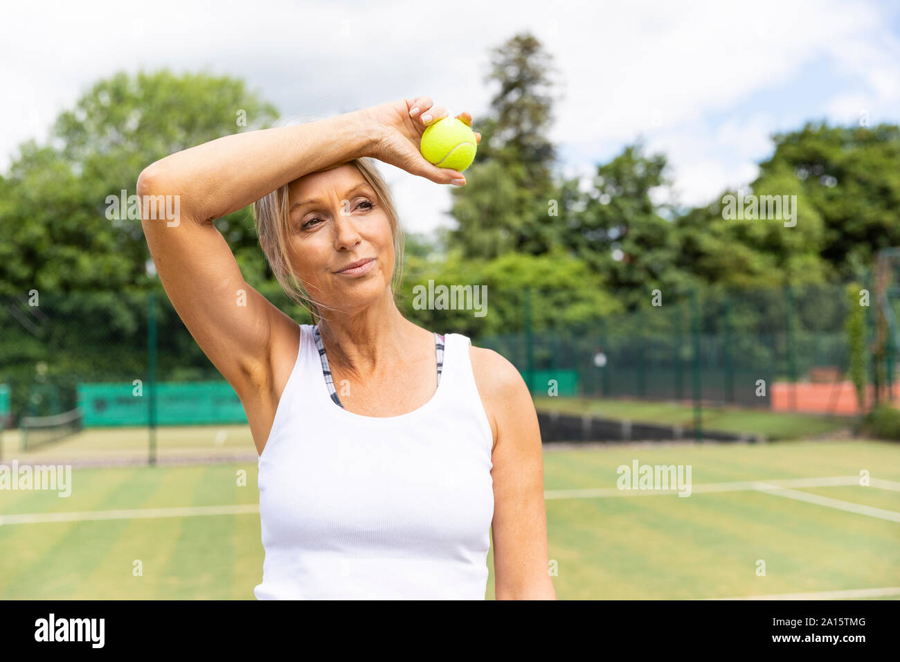 Stanco di tennis femminile player prendendo una pausa sull'erba corte al tennis club Foto Stock