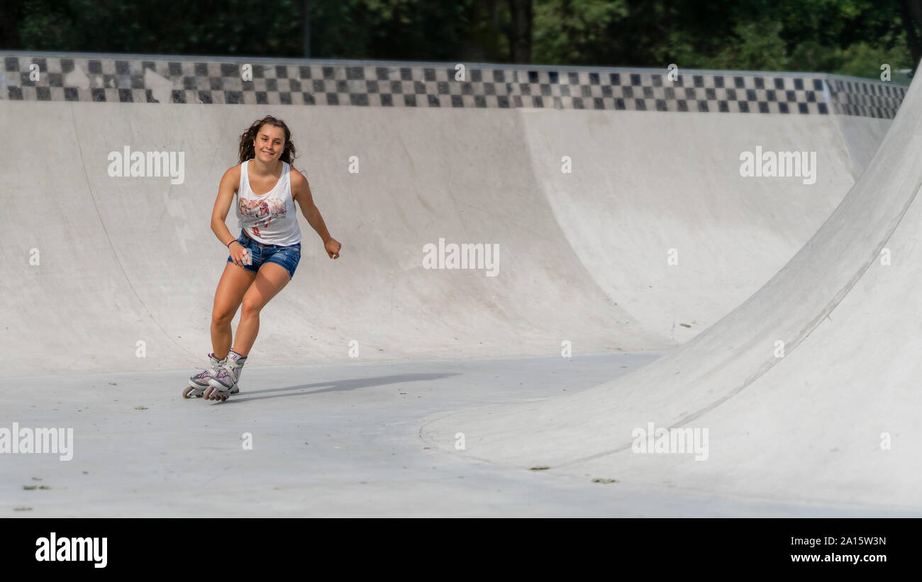 Giovane donna inline skating in skatepark Foto Stock