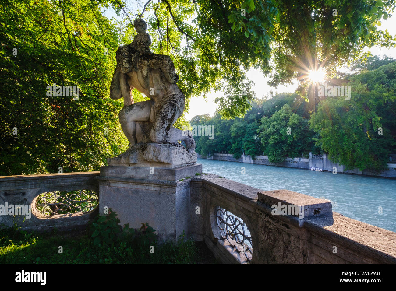 In Germania, in Baviera, Monaco, San Cristoforo statua circondata da alberi da fiume Isar al tramonto Foto Stock