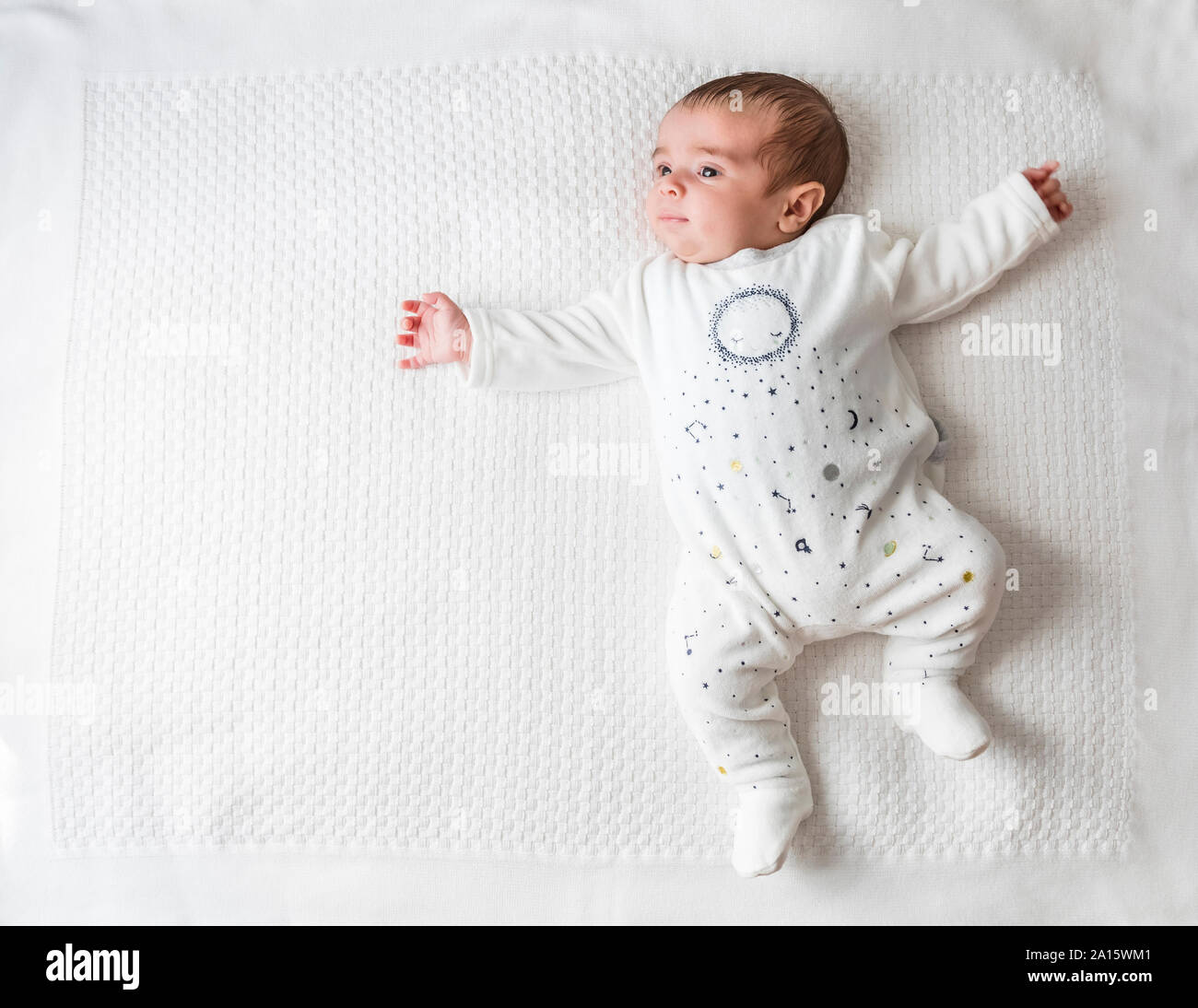 Baby boy posa in letto oltre coltre bianca Foto Stock