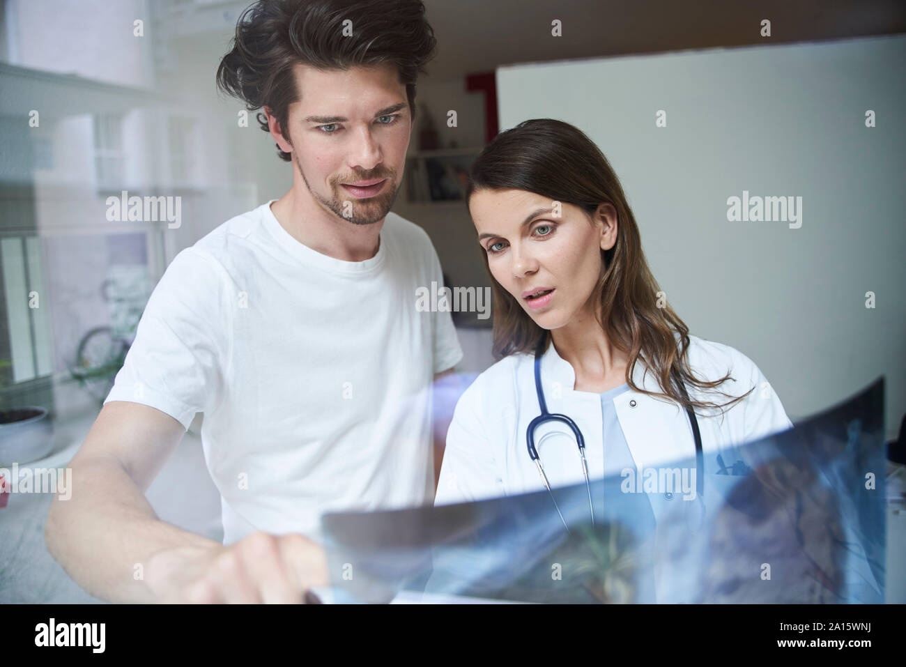 Due medici con l'immagine a raggi x dietro il vetro di finestra Foto Stock