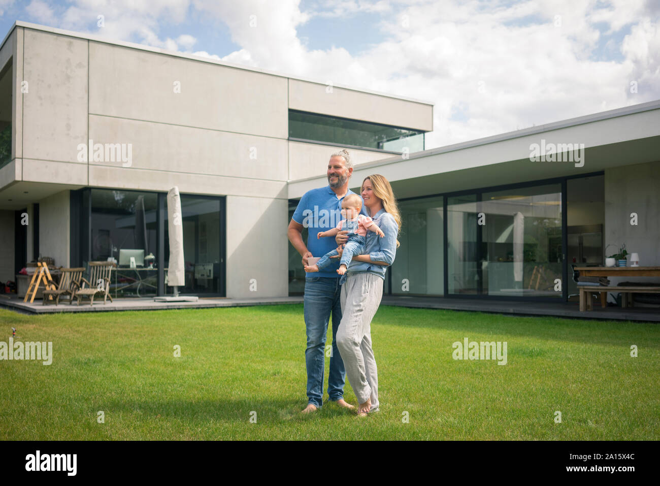 Famiglia di tre persone in piedi nel giardino della loro casa Foto Stock