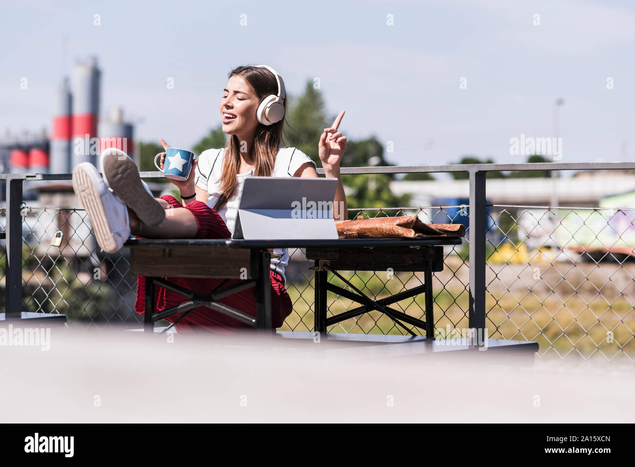 Giovane donna rilassante in un giardino della birra con cuffie e tablet Foto Stock