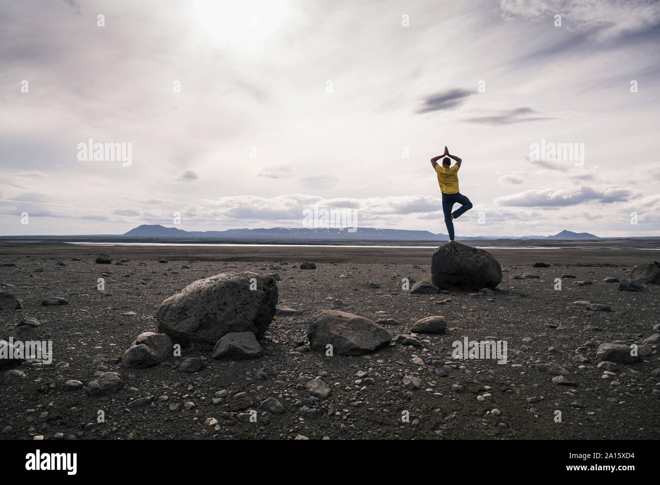 Uomo maturo in equilibrio su una gamba sola su una roccia nelle Highlands vulcaniche di Islanda Foto Stock