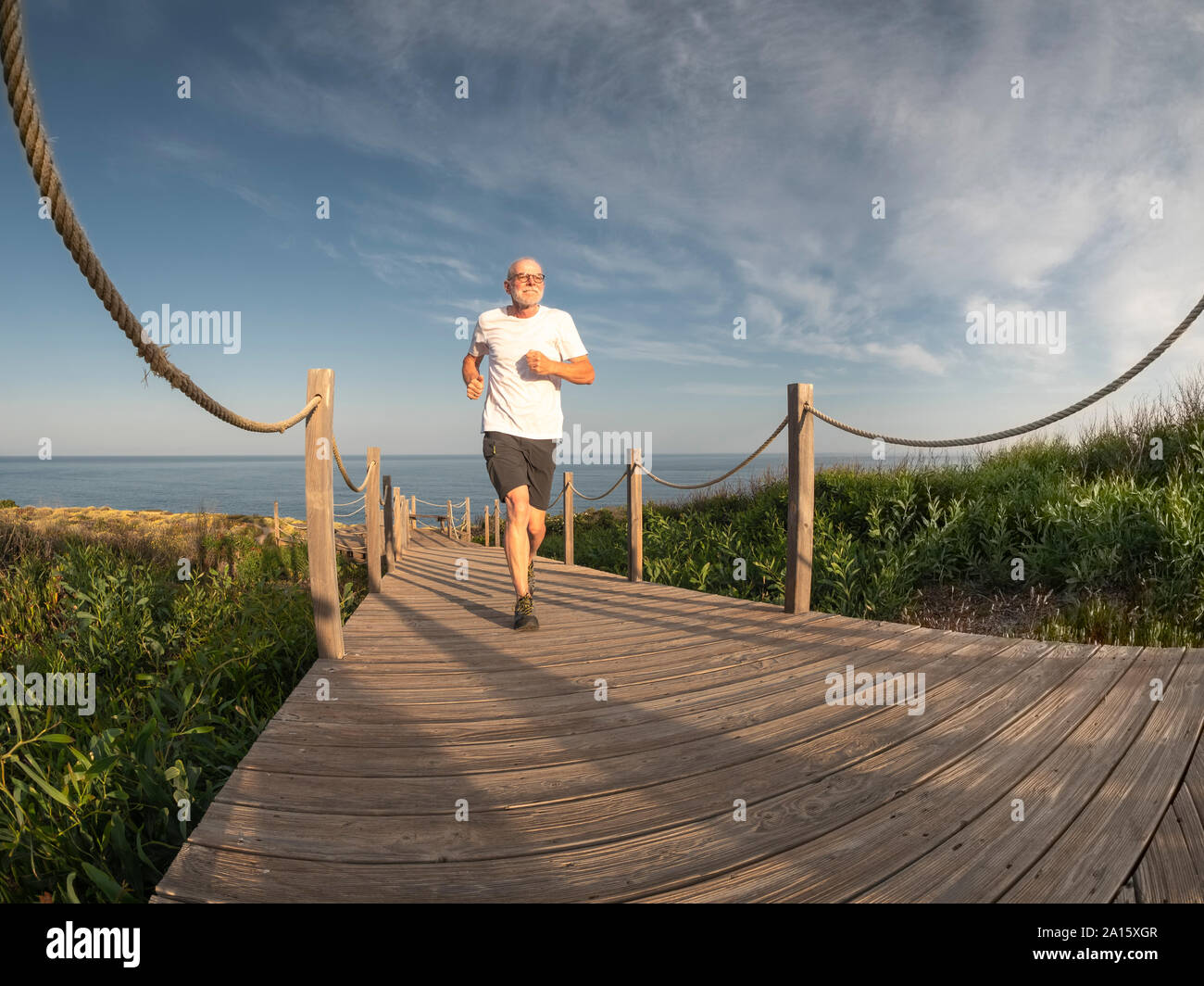 Portogallo Alentejo, senior uomo jogging sulla passerella in legno Foto Stock