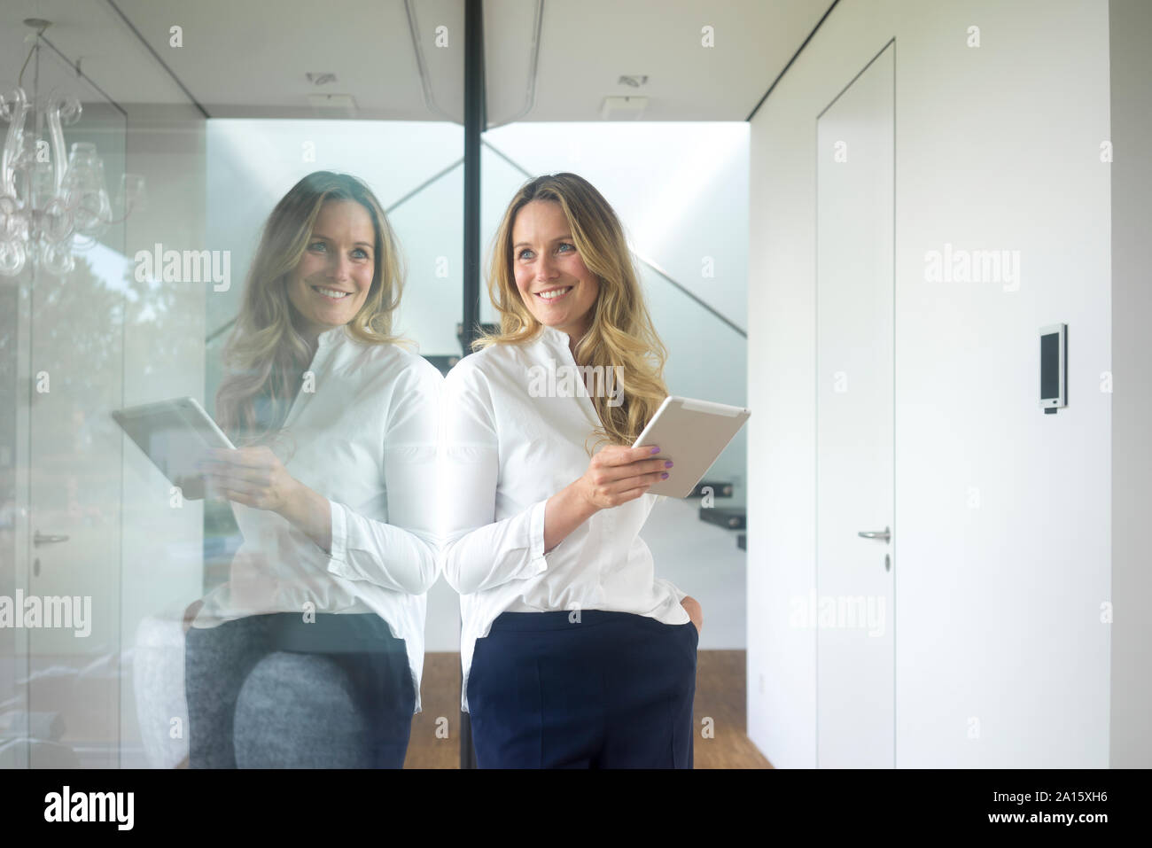 Sorridente imprenditrice azienda tablet in casa moderna Foto Stock