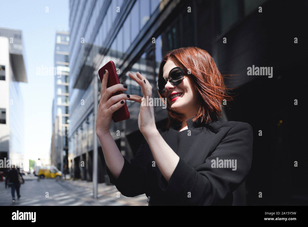 Donna elegante tenendo selfies nella città Foto Stock
