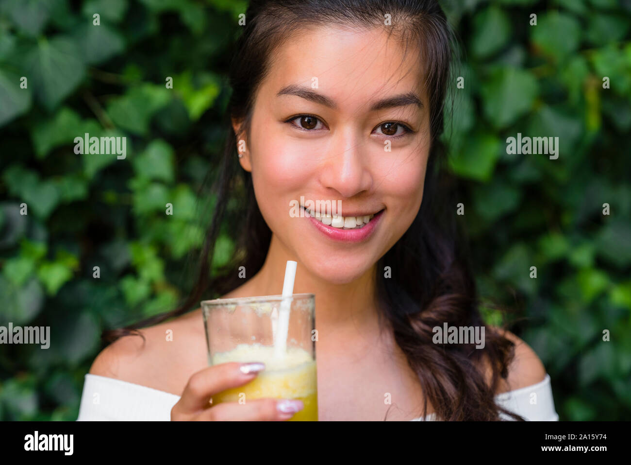 Ritratto di sorridente giovane donna in possesso di una bibita salutare Foto Stock