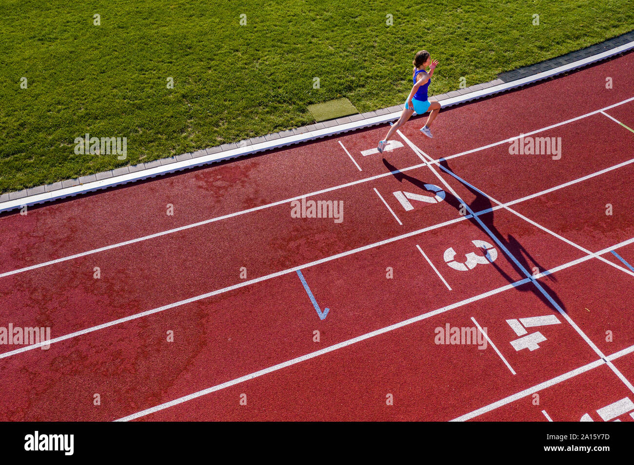 Vista aerea di esecuzione di un giovane atleta femminile su una pista di tartan Attraversamento linea di finitura Foto Stock