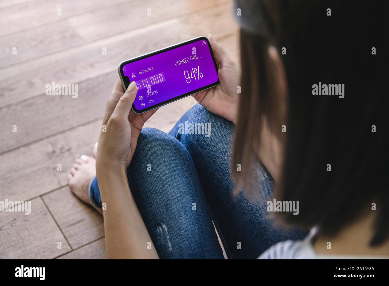 Giovane donna con smartphone con smart home funzioni di controllo Foto Stock